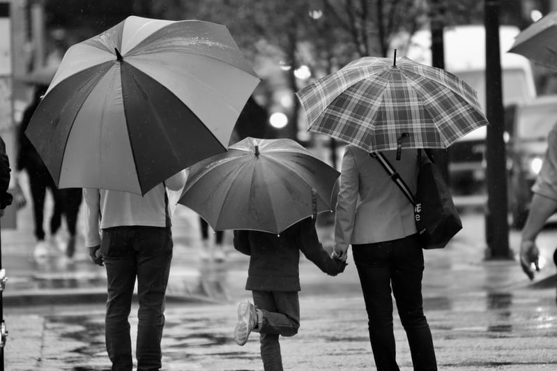família na rua com guarda-chuva 